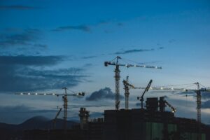 Vue d’un chantier de construction au crépuscule avec plusieurs grues en activité au-dessus d’immeubles en développement, illustrant la croissance du secteur de la construction et la forte demande en main-d’œuvre spécialisée au Québec.